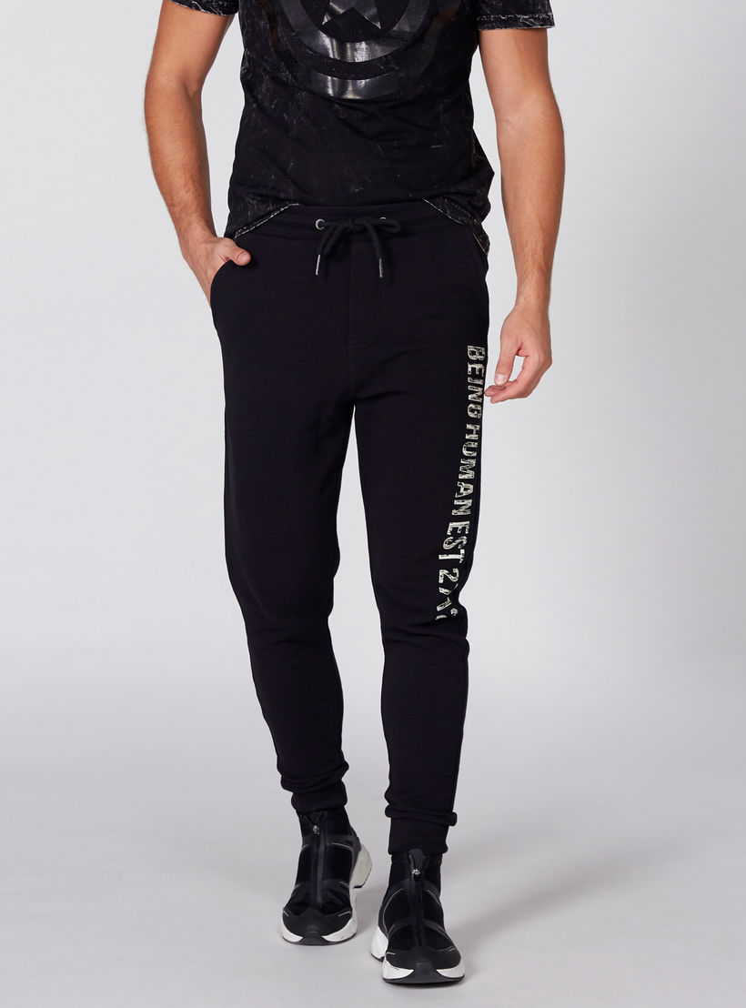 بنطال رياضي طويل بخصر مطّاطي وطبعات بيينج هيومن-men-clothing-bottoms-joggers-image-1